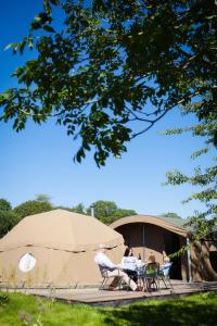 duas pessoas sentadas numa mesa em frente a uma tenda em Durrell Wildlife Camp em Trinity