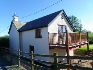 a small white house with a wooden deck at Headgate Farm Bed and Breakfast in Twitchen