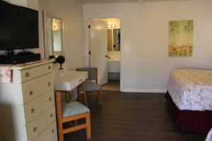 Schlafzimmer mit einem Bett und einer Kommode mit einem TV in der Unterkunft Mariners Cove Inn in Westport