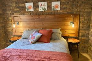 a bed with a wooden headboard and pillows on it at Thala Thala Private Villa in the bush-veld in Cullinan +10 photos