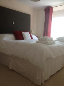 1 cama con sábanas blancas, almohadas rojas y ventana en Headgate Farm Bed and Breakfast, en Twitchen