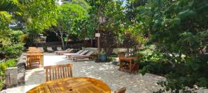 un patio con sillas de madera, mesas y árboles en Bara Beach Bungalows, en Bira