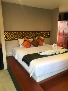 a bedroom with two beds with white sheets and orange pillows at Royal Phawadee Village Patong - SHA Plus in Patong Beach