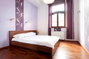 een slaapkamer met een bed en een raam met paarse gordijnen bij DaVinci Radziwiłłowska Apartments in Krakau