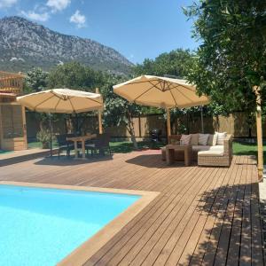 a patio with two umbrellas and a swimming pool at Dedemuem Adrasan in Kumluca