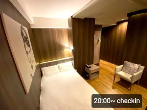 Petit Hotel mio في سايتاما: غرفه فندقيه بسرير وكرسي