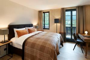 a bedroom with a bed and a desk and windows at Eiger View Alpine Lodge in Grindelwald