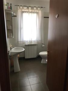 a bathroom with a sink and a toilet and a window at Affittacamere Fiumicello in Papariano