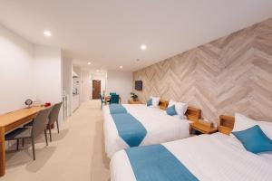 a hotel room with two beds and a desk at Hotel Santa Barbara Miyakojima Resort in Miyako-jima