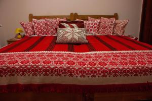 a bed with a red and white bedspread and pillows at Nyikó Vendégház in Lupeni