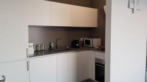 a kitchen with white cabinets and a microwave at IL SOGNO 1 Piscina e vista lago in Torri del Benaco