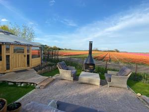 a patio with chairs and a fireplace in front of a field of flowers at Basic luxury yurt in Egmond aan den Hoef