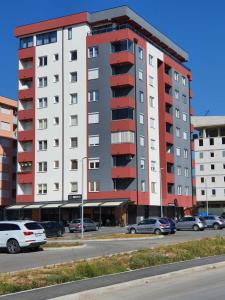 een hoog gebouw met auto's geparkeerd op een parkeerplaats bij S&D Apartman in Lukavica