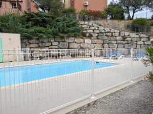 una valla alrededor de una piscina con una pared de piedra en Maisonnette dans domaine avec piscine à Nyons, pays des olives, en Nyons