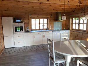 eine Küche mit weißen Geräten und einem Tisch in einer Hütte in der Unterkunft Le Chalet Caux-Marin in Tourville-la-Chapelle
