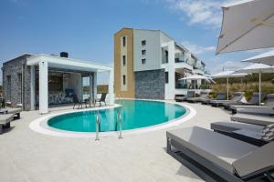 a swimming pool with lounge chairs and a building at GreyStone Suites in Paralia Dionysiou