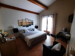 a bedroom with a bed and a chair and a window at Villa Asunda B&B Spa & Sauna, Chambres d'Hôtes in Saint-Maximin-la-Sainte-Baume