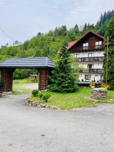 un grand bâtiment avec un toit noir et un arbre dans l'établissement Pensiunea Pietrosul, à Borşa