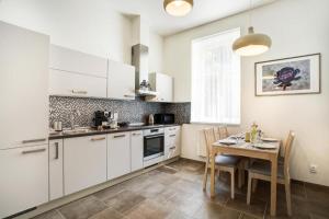 kuchnia z białymi szafkami i stołem z krzesłami w obiekcie Apartman Karlovarská w Mariańskich Łaźniach