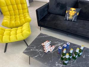 ein Wohnzimmer mit einem gelben Sessel und einem Tisch mit Bierflaschen in der Unterkunft New! Luxus Holon for 11 people (5min from TLV) in Cholon