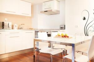 a kitchen with white cabinets and a table with fruit on it at DaVinci Radziwiłłowska Apartments in Krakow