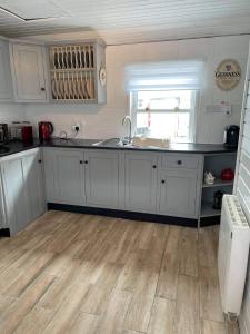 a kitchen with white cabinets and a wooden floor at Dream Cottage in Ballintober
