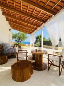 un patio con mesas y sillas de madera y un sofá en Joyas cosy apartment, en Tragaki