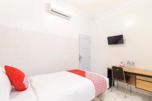 a bedroom with a bed and a desk with a computer at OYO Life 966 Dinda Guesthouse in Yogyakarta