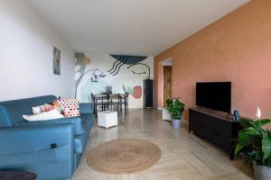a living room with a blue couch and a tv at Sea view apartment in residence with swimming pool! in Nice