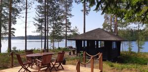 a gazebo with a table and chairs next to a lake at Mäntyniemi in Petäjävesi