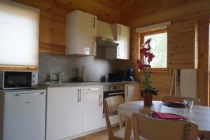 a kitchen with white cabinets and a table and a window at Chalet au Natur'Heil Nature-Spa-Gourmandise in Wahlbach