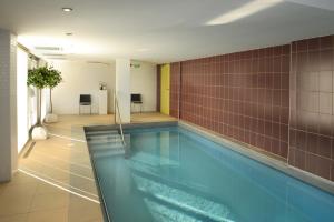 a swimming pool in a room with brown tiles at DOMITYS Le Parc de Saint-Cloud in Cambrai