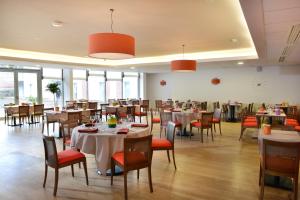 a dining room with tables and chairs and windows at DOMITYS Le Parc de Saint-Cloud in Cambrai