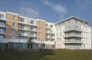 un gran edificio de apartamentos con césped delante en DOMITYS Le Parc de Saint-Cloud, en Cambrai