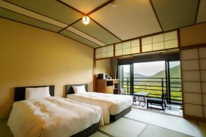 a hotel room with two beds and a balcony at Hakone Kowakien Mikawaya Ryokan in Hakone