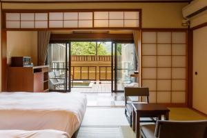 Schlafzimmer mit einem Bett und einer Tür zu einer Terrasse in der Unterkunft Hakone Kowakien Mikawaya Ryokan in Hakone