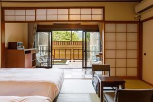 a bedroom with a bed and a door to a patio at Hakone Kowakien Mikawaya Ryokan in Hakone