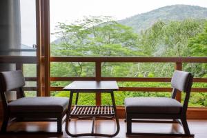 two chairs and a table in front of a window at Hakone Kowakien Mikawaya Ryokan in Hakone