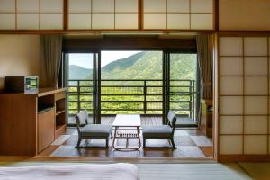 een kamer met een tafel en stoelen en een groot raam bij Hakone Kowakien Mikawaya Ryokan in Hakone