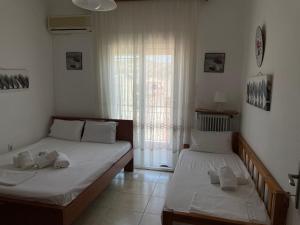 two beds in a room with a window at Nikos Rooms in Nea Peramos