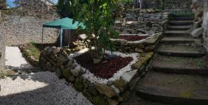 Casa do Horreo في Puentecesures: جدار عازل حجري مع شجرة ومظلة