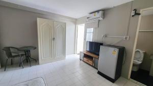 a small kitchen with a refrigerator and a table in a room at RoomQuest Bangkok Ratchada in Bangkok