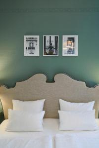 łóżko z czterema zdjęciami na zielonej ścianie w obiekcie Hotel Monopol - Central Station w Frankfurcie nad Menem