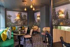 restauracja ze stołami, krzesłami i obrazami na ścianach w obiekcie Hotel Fior d'Aliza w Paryżu