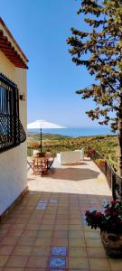 a patio with a bench and a table and a tree at villa immersa in oliveto vista mare in Sciacca