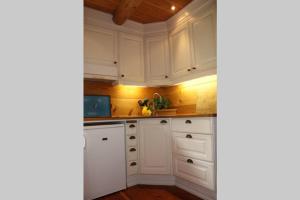 a white kitchen with white cabinets and wooden floors at Drengastova Hardangerfjord in Lofthus