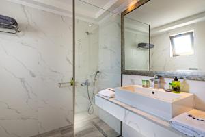 a bathroom with a sink and a shower and a mirror at Delfina Boutique Hotel in Georgioupolis