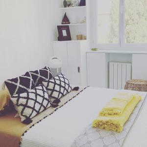 ein weißes Bett mit schwarzen und weißen Kissen darauf in der Unterkunft La Maison narbonnaise in Narbonne