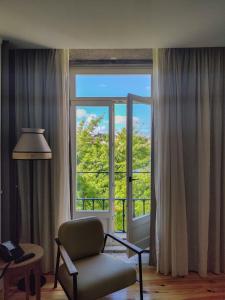 a living room with a chair and a large window at Memoria Porto FLH Hotels in Porto