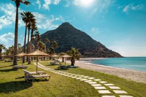 a beach with palm trees and a mountain at Radisson Collection Hotel, Bodrum in Akyarlar